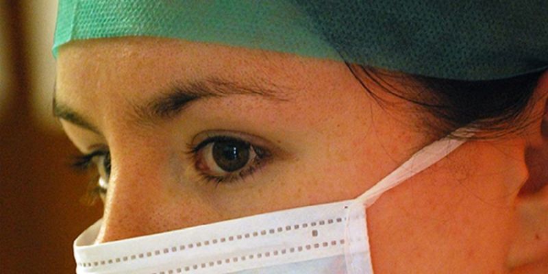 A young female veterinary surgeon wearing a surgical hat and facemask 