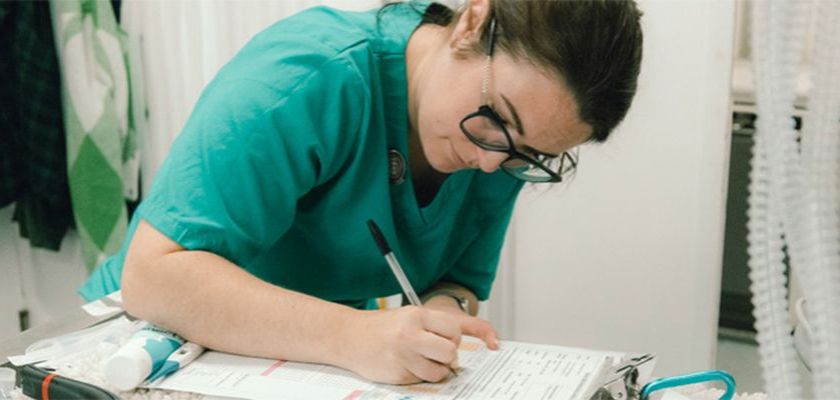 A female vet student fills in a form while sitting at a desk 