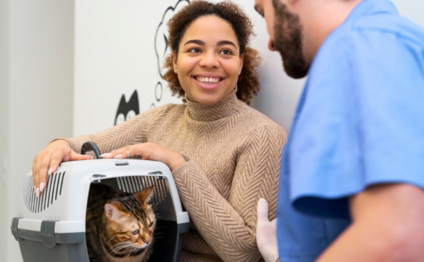 Picture of animal owner holding a cat in a cat carrier speaking with a veterinary professional