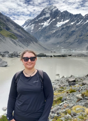 Beth Duffill-Brookes pictured standing smiling while on a hike with a mountainous backdrop