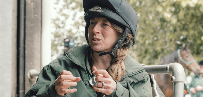 A female instructor wearing a riding helmet at an equestrian facility 