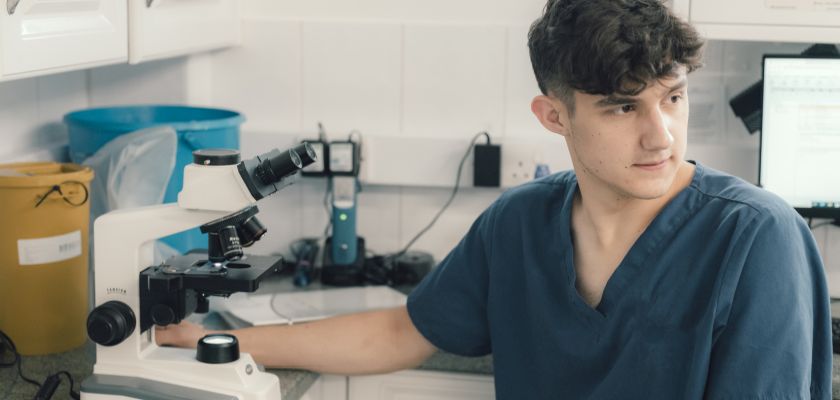 A young male vet student with a microscope