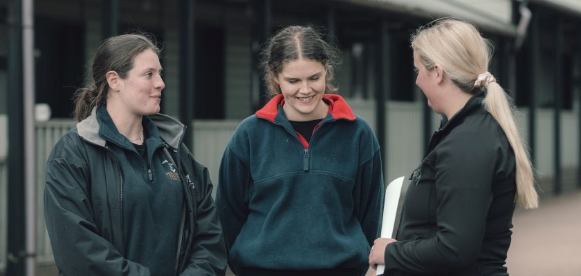 Two female vet students laughing with a female instructor 